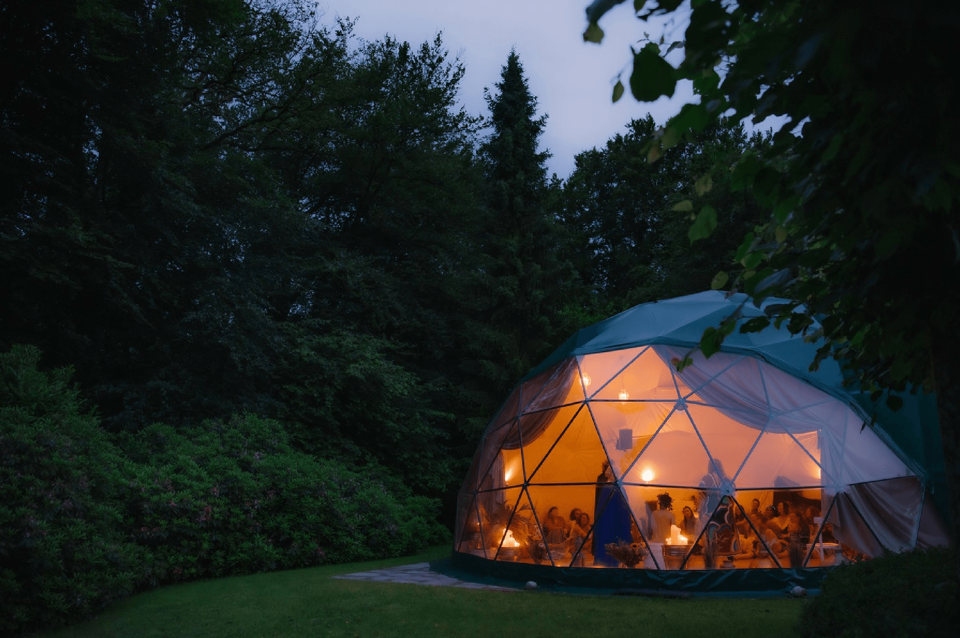 The geodesic Dome glowing at night beside the House